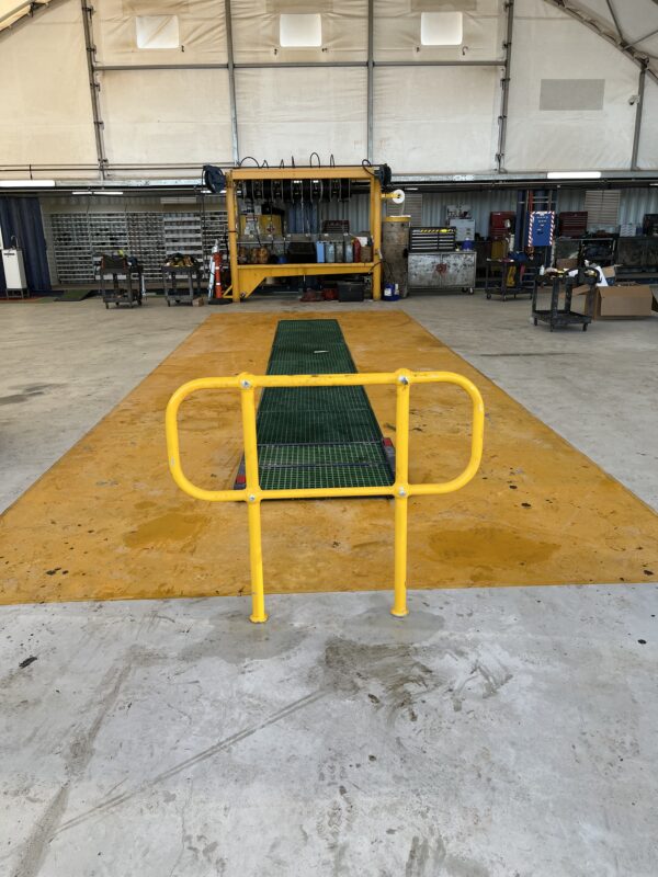 Workshop concrete floor with safety railing and grating covering service pit